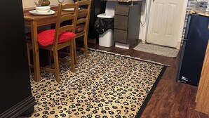 A kitchen with a brick wall, a dining table with chairs, a refrigerator, and a patterned rug. - Tiny home for  short and long term also (Sugar Land)