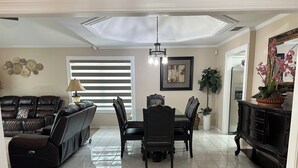 A living room with a sofa, dining table, chairs, and a TV.
