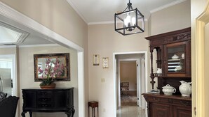 A spacious hallway with a black console table, a mirror, and a hanging light fixture.