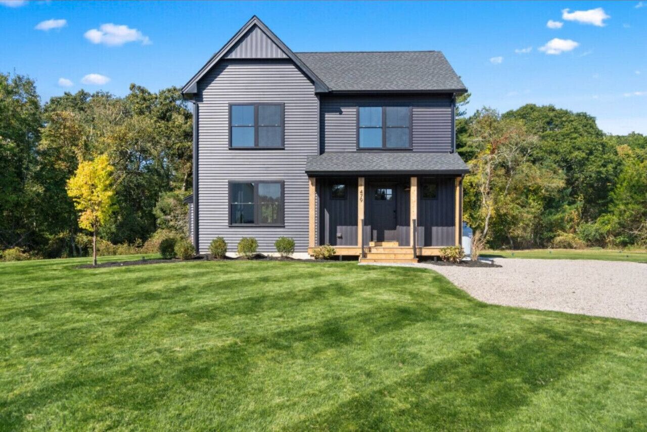 A two-story house with a front porch, a driveway, and a well-maintained lawn.