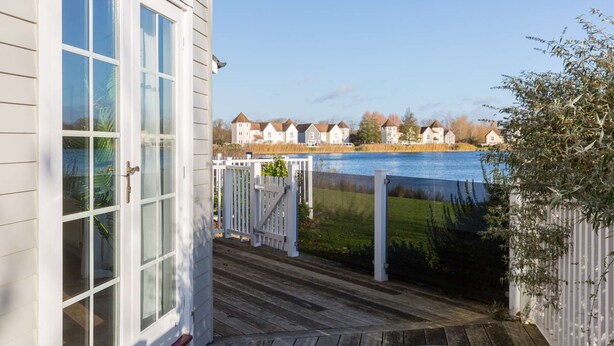 A wooden deck with a view of a lake and houses in the background.