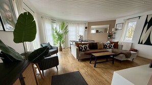 A modern living room with a sofa, coffee table, and a large plant.