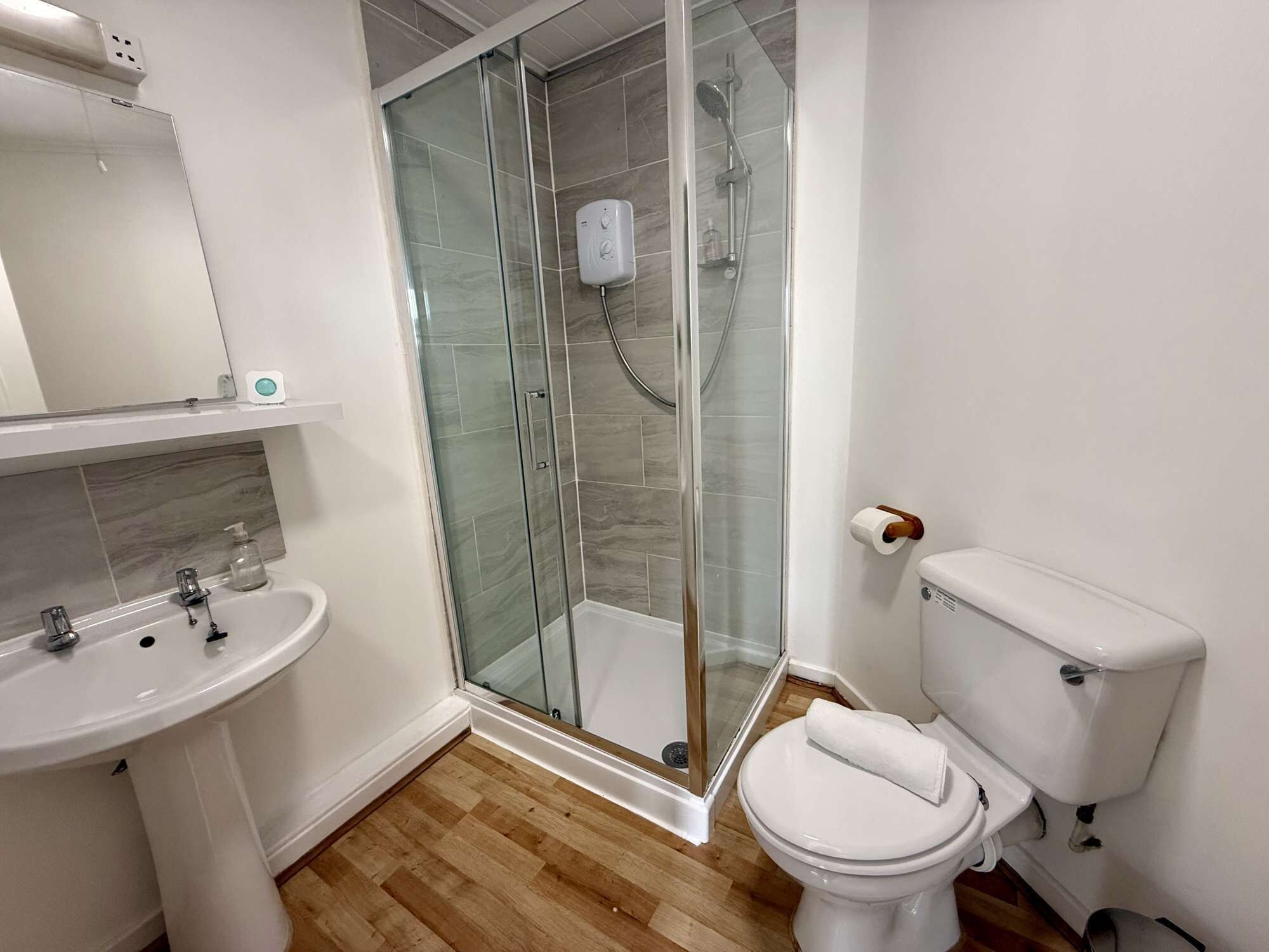 A modern bathroom with a glass-enclosed shower, a white sink, and a toilet.