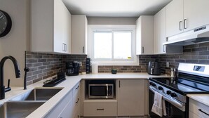 Een moderne keuken met witte kasten, een zwarte kookplaat, een magnetron en een spoelbak.