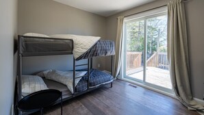 Een slaapkamer met stapelbedden en uitzicht op een houten terras door een grote schuifdeur.