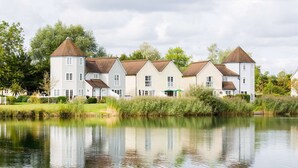 A row of white houses with brown roofs by a calm lake. - Broadway house, 3 bedroom and dog friendly (Windrush Lake)