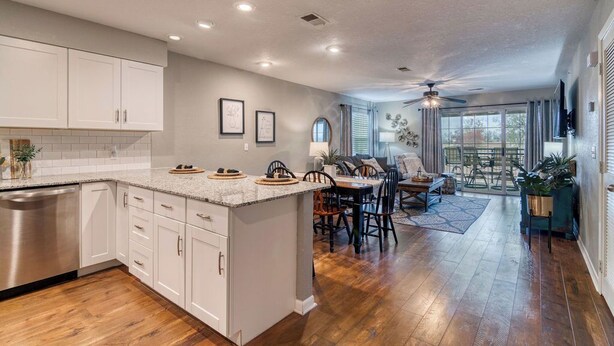 A spacious kitchen with white cabinets, a large island, and a dining area with a table and chairs.