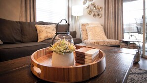 A round wooden tray with a glass container holding a succulent plant, placed on a dark wooden coffee table in a living room.