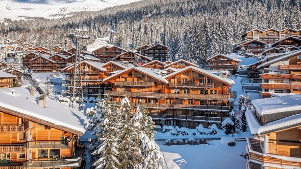 A snow-covered resort with wooden cabins and a ski lift.