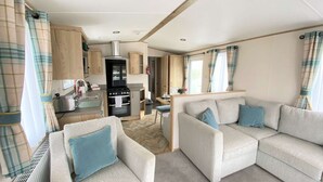 Ein kompaktes Wohnmobil-Interieur mit einer Küchenzeile, zwei Sofas und einem Essbereich.