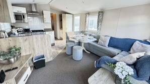 Un espacio habitable moderno y funcional con kitchenette, comedor y un conjunto de sofás.