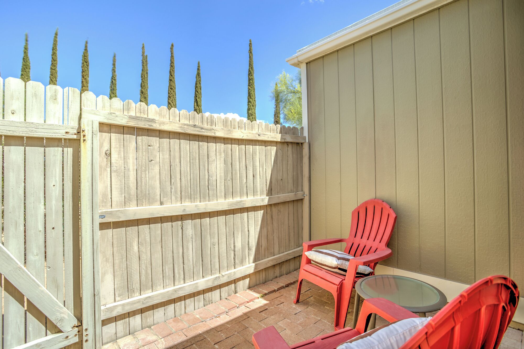 A patio area with a wooden fence, a red chair, and a small table.