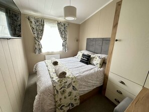 Ett sovrum med en säng, en garderob, ett element och gardiner.