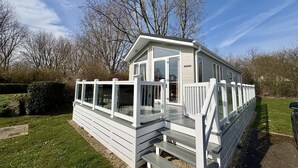 A single-story mobile home with a deck and a covered porch.