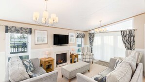 A living room with a fireplace, a television, and a view of the outside.