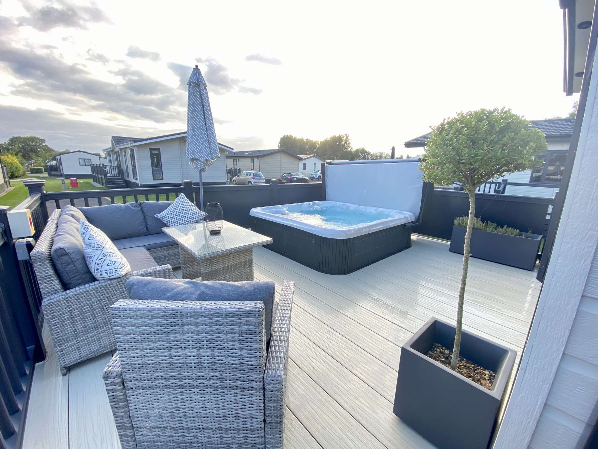 Eine Terrasse mit Korbmöbeln, einem Whirlpool und einem Blumentopf-Baum.