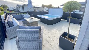 A deck with wicker furniture, a hot tub, and a potted tree. - Burford Hot Tub Holiday Home (Hoburne Holiday Park)