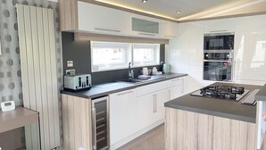 A modern kitchen with white cabinets, a built-in oven, and a gas stove. - Spring Lodge with private hot tub (Hoburne Holiday Park)