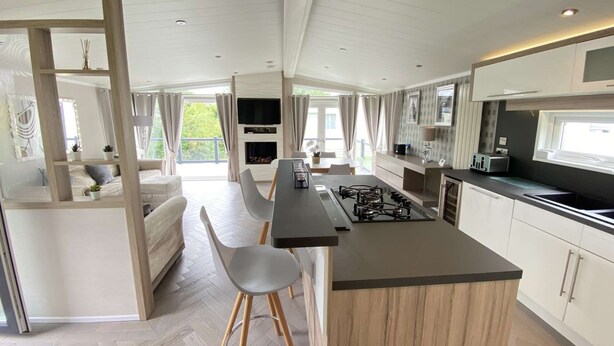 A modern kitchen with a central island, bar stools, and a dining area. - Spring Lodge with private hot tub (Hoburne Holiday Park)