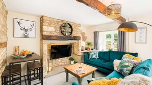 Una sala de estar acogedora con chimenea de piedra, sofá color turquesa, mesa de centro de madera y un comedor con mesa y sillas rústicas.