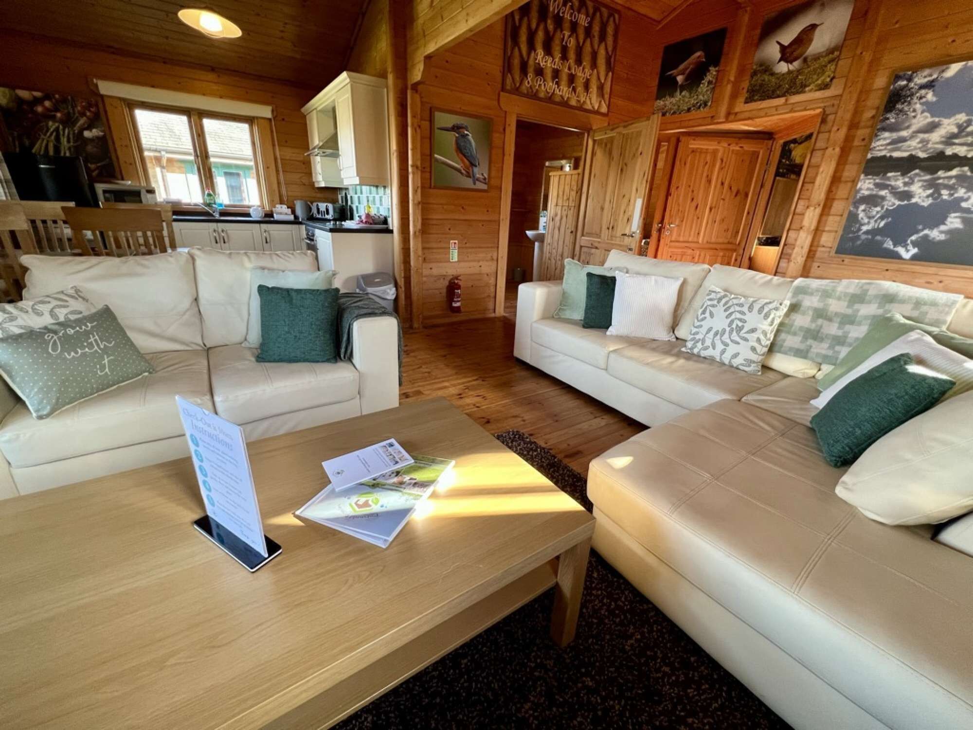 Interior acogedor de una cabaña con dos sofás blancos, una mesa de centro de madera y una zona de cocina.