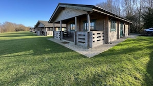 A rustic lodge with a covered porch and outdoor seating area, surrounded by a well-maintained lawn and trees.