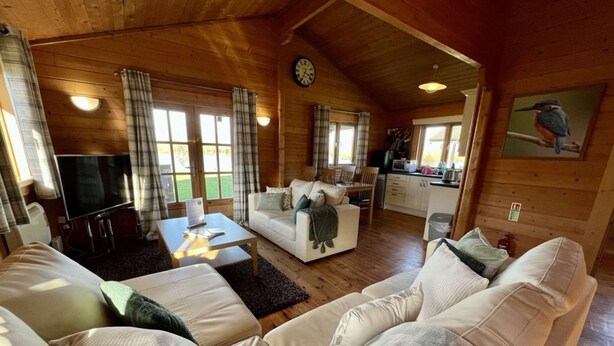 A cozy cabin interior with a living area featuring a sofa set, a coffee table, and a television.