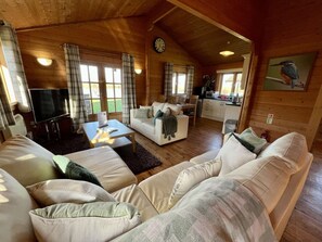 L’intérieur chaleureux d’un chalet comprend un espace de vie avec un canapé, une table basse et un téléviseur.