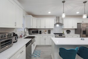 Enjoy cooking in this well-lit kitchen with a stainless steel range, oven, and spacious island with seating.