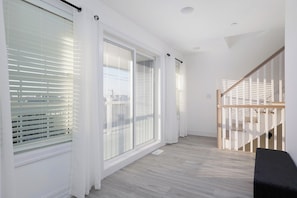 Experience a bright and airy space with a sliding glass door leading to an outdoor area, a simple staircase, and a clean floor.