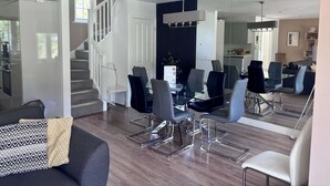 Un espacio de sala moderno con una escalera, una mesa de comedor con sillas y un sofá.