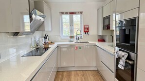 Una cocina moderna con extractor de acero inoxidable, horno empotrado y ventana con vistas.