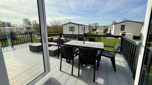 Une terrasse dotée de mobilier d’extérieur, d’une porte vitrée et offrant une vue sur des maisons mobiles.