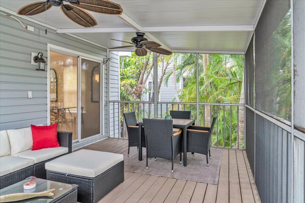 A covered outdoor area with a sofa, table, chairs, and ceiling fans.