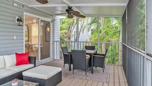 A covered outdoor area with a sofa, table, chairs, and ceiling fans.