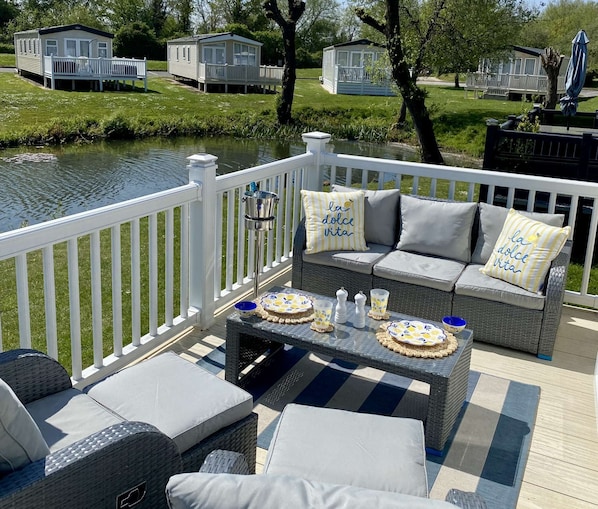 A deck with outdoor furniture, a table with decorative plates, and a view of a lake.