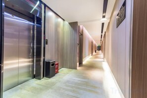 A hotel corridor with elevators, a trash bin, and a sign on the wall. - Rest Comfort Hotel (Wenzhou Lucheng) (Wenzhou)