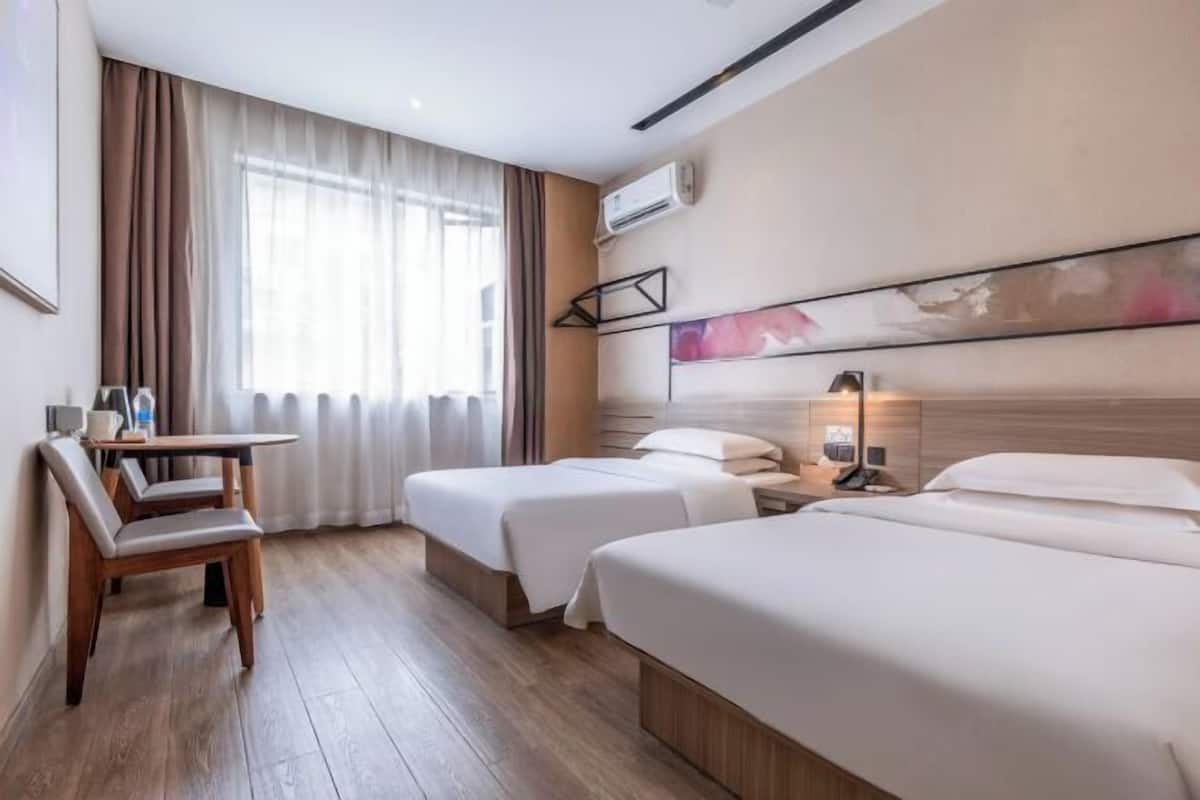 A hotel room with two beds, a desk, and a chair.