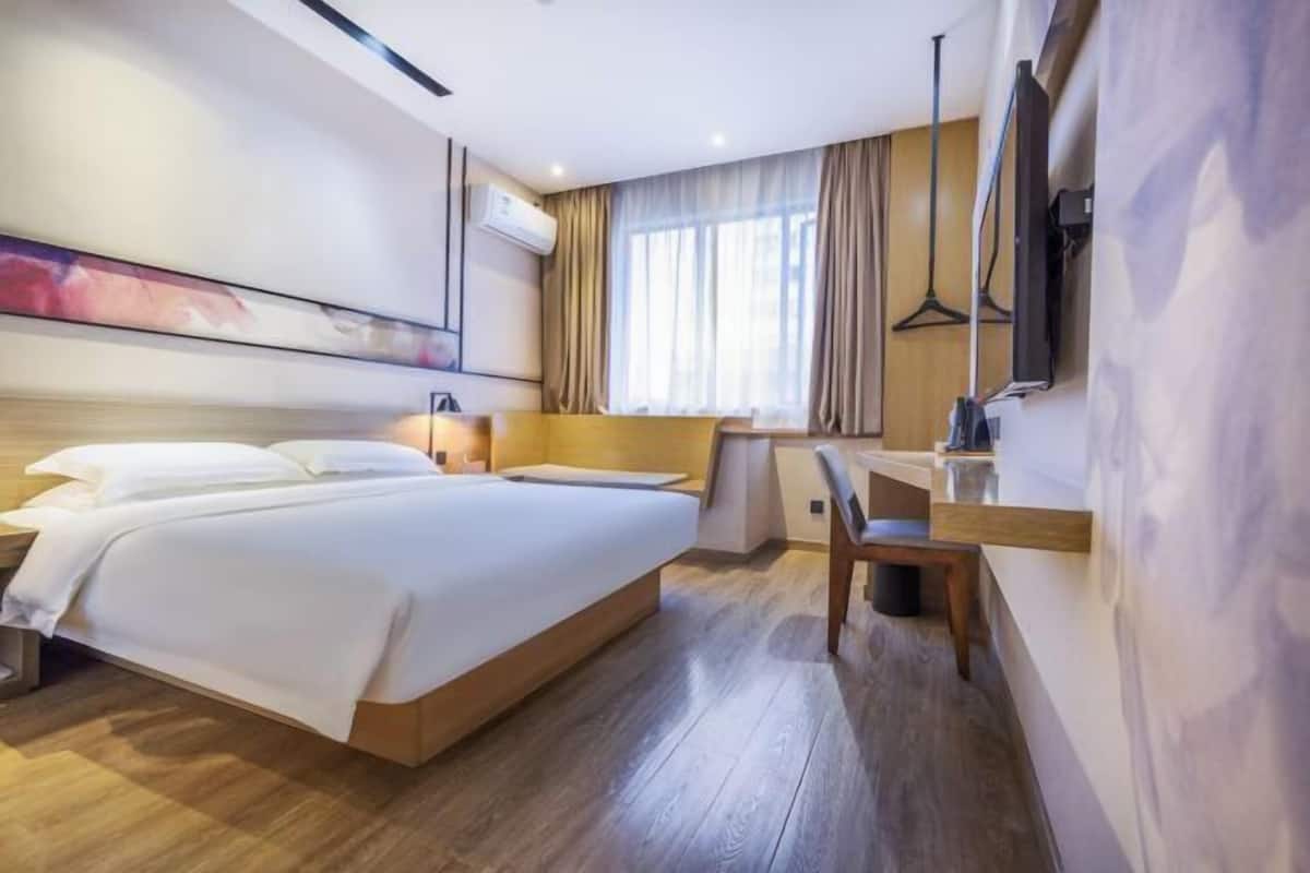 A modern hotel room with a large bed, a desk, and a chair.