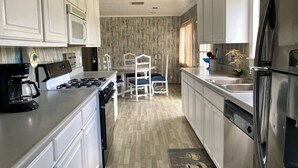 A modern kitchen with white cabinets, a stainless steel refrigerator, a gas stove, and a coffee maker. - Rancho Dominique Valle de Guadalupe (Valle de Guadalupe)