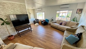 A spacious living room with a large flat-screen TV, multiple sofas, a coffee table, and a potted plant. - Rancho Dominique Valle de Guadalupe (Valle de Guadalupe)
