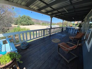 A covered porch with wooden flooring, a white railing, and two rocking chairs.