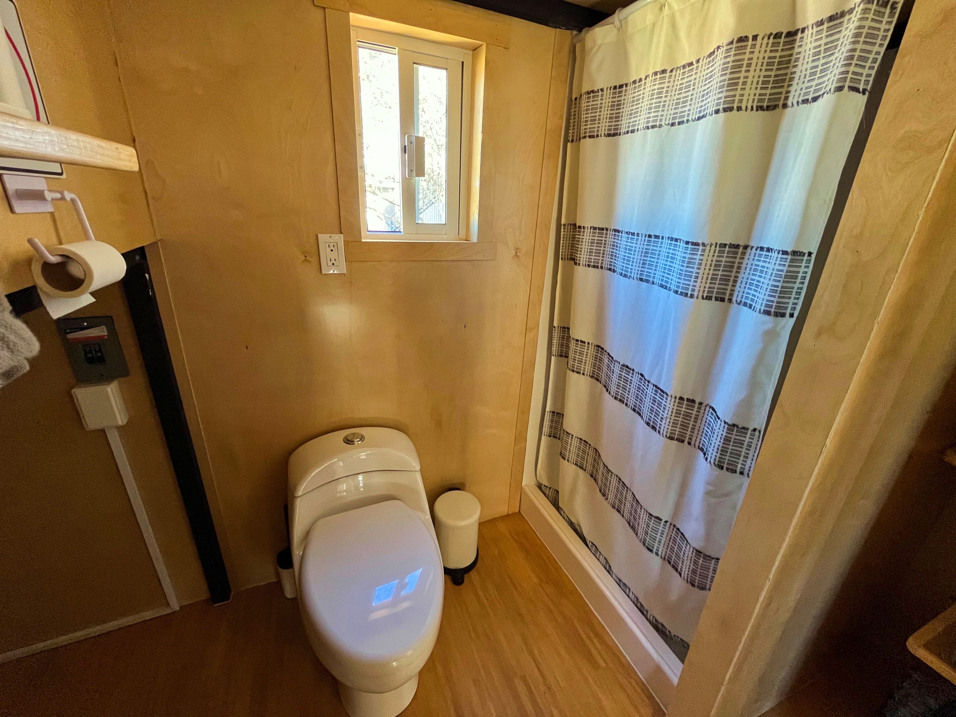 A small bathroom with a toilet, a window, and a shower curtain.