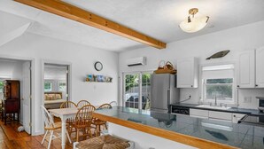 Une cuisine moderne avec des meubles blancs, un grand îlot central doté d’un plateau en verre et des chaises en bois.
