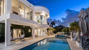 A modern multi-story house with a swimming pool, outdoor seating, and a covered patio area. - Villa Seminole: Luxurious Waterfront Retreat with Pool, Gym & Hot Tub (Fort Lauderdale)
