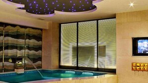A modern indoor swimming pool with a starry ceiling, a large window with blinds, and a television mounted on the wall. - Ruixin Hotel (Fuqing)