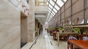A spacious indoor area with marble flooring, wooden tables and chairs, and a high ceiling with a skylight. - Ruixin Hotel (Fuzhou)