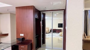 A modern room with a glass desk, a wooden cabinet, a sliding glass door leading to a bedroom, and a flat-screen TV mounted on the wall. - Ruixin Hotel (Fuqing)