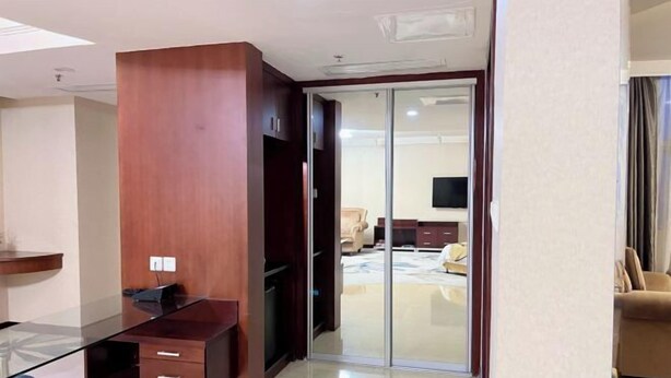 A modern room with a glass desk, a wooden cabinet, a sliding glass door leading to a bedroom, and a flat-screen TV mounted on the wall. - Ruixin Hotel (Fuzhou)