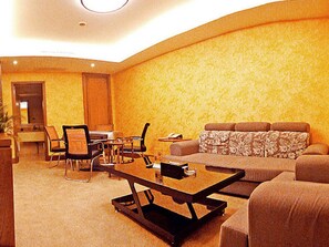 A living room with a sofa, a coffee table, a dining table with chairs, and a television. - Ruixin Hotel (Fuzhou)
